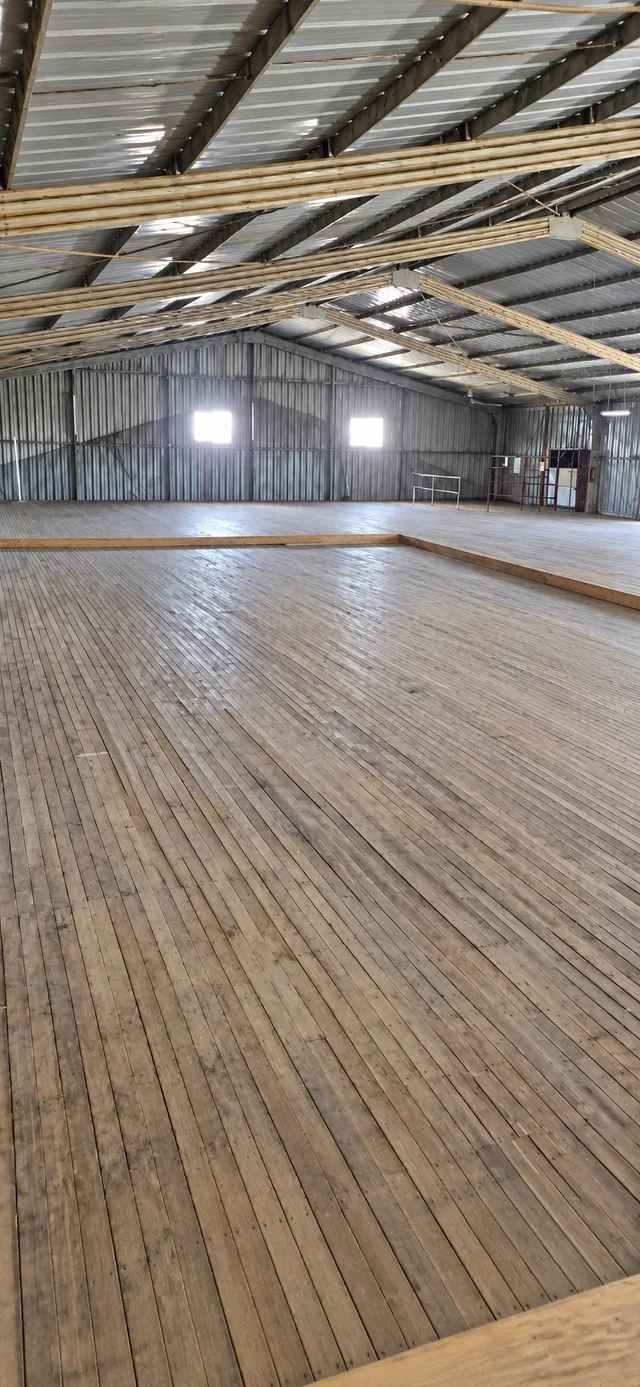 Vista histórica de un interior con piso de tablas y estructura de cubierta metálica